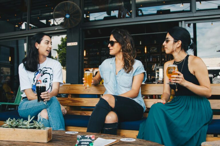 A group of women in conversation enjoying drinks at an outdoor bar.