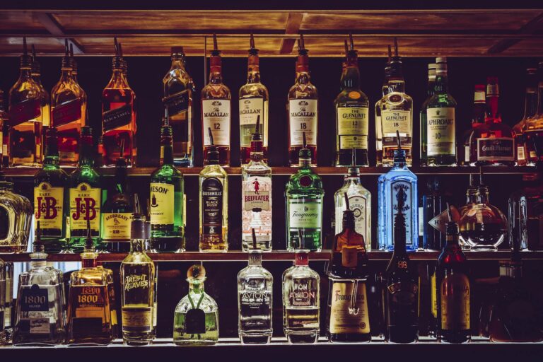 An array of various liquor bottles beautifully displayed on a bar shelf.