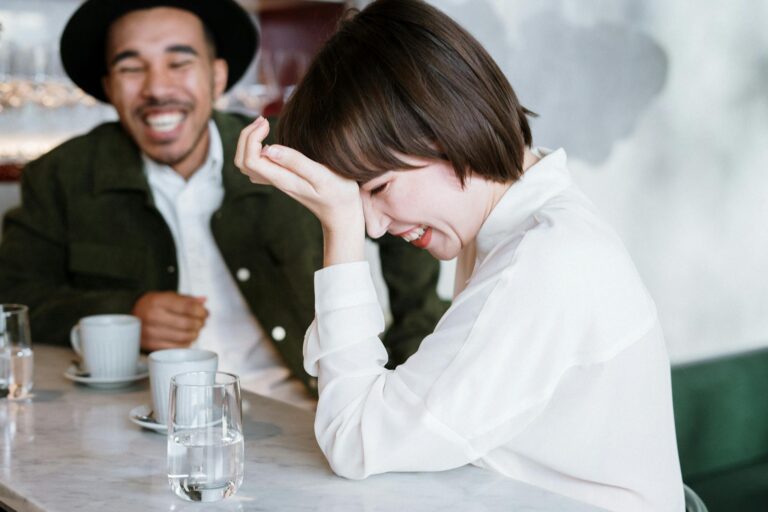 Laughing couple at a café table, enjoying a friendly and cheerful conversation.